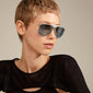 YANARA sunglasses blue/gold: Woman with short hair wearing stylish pilot-design sunglasses, featuring blue lenses and gold frames, embodying retro 70s vibes.