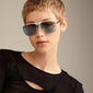 YANARA sunglasses in a classic pilot design, featuring gold frames and blue lenses, worn by a woman with short hair, reflecting retro 70s style.