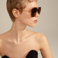 Woman with short hair wearing oversized Aliet sunglasses from Pilgrim, featuring a tortoise brown frame with a retro vibe and dark green lenses.