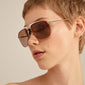 YANARA sunglasses brown/gold featuring a sporty pilot design with light brown lenses and colorful metal frames, worn by a woman with short hair.