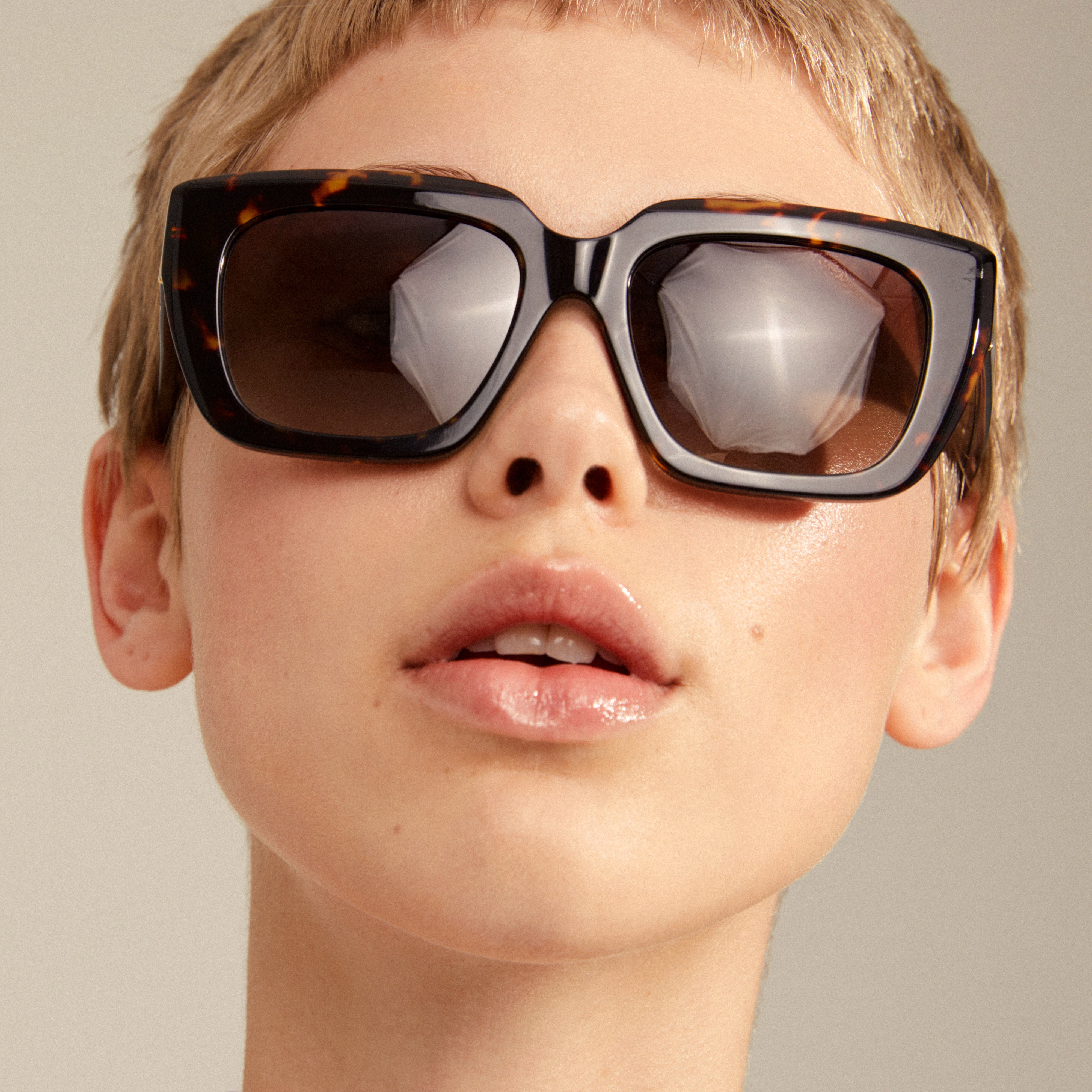 JOGLI sunglasses tortoise brown/gold, oversized with sharp frames and golden hinge details, worn by a person showcasing eyewear style from Pilgrim.