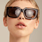 JOGLI sunglasses tortoise brown/gold, oversized with sharp frames and golden hinge details, worn by a person showcasing eyewear style from Pilgrim.