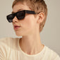 ENIEL sunglasses in tortoise brown/gold, featuring a classic design with dark lenses, worn by a woman with short hair, embodying a stylish summer look.