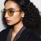 Woman wearing Pilgrim's iconic DALLAS sunglasses in yellow/gold, showcasing a classic pilot style. Sunglasses offer UVA/UVB protection with a sustainable pouch.