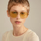 Woman wearing Pilgrim's DALLAS sunglasses yellow/gold, showcasing iconic pilot style with UVA/UVB protection. Ideal for trendsetters and adventure seekers.