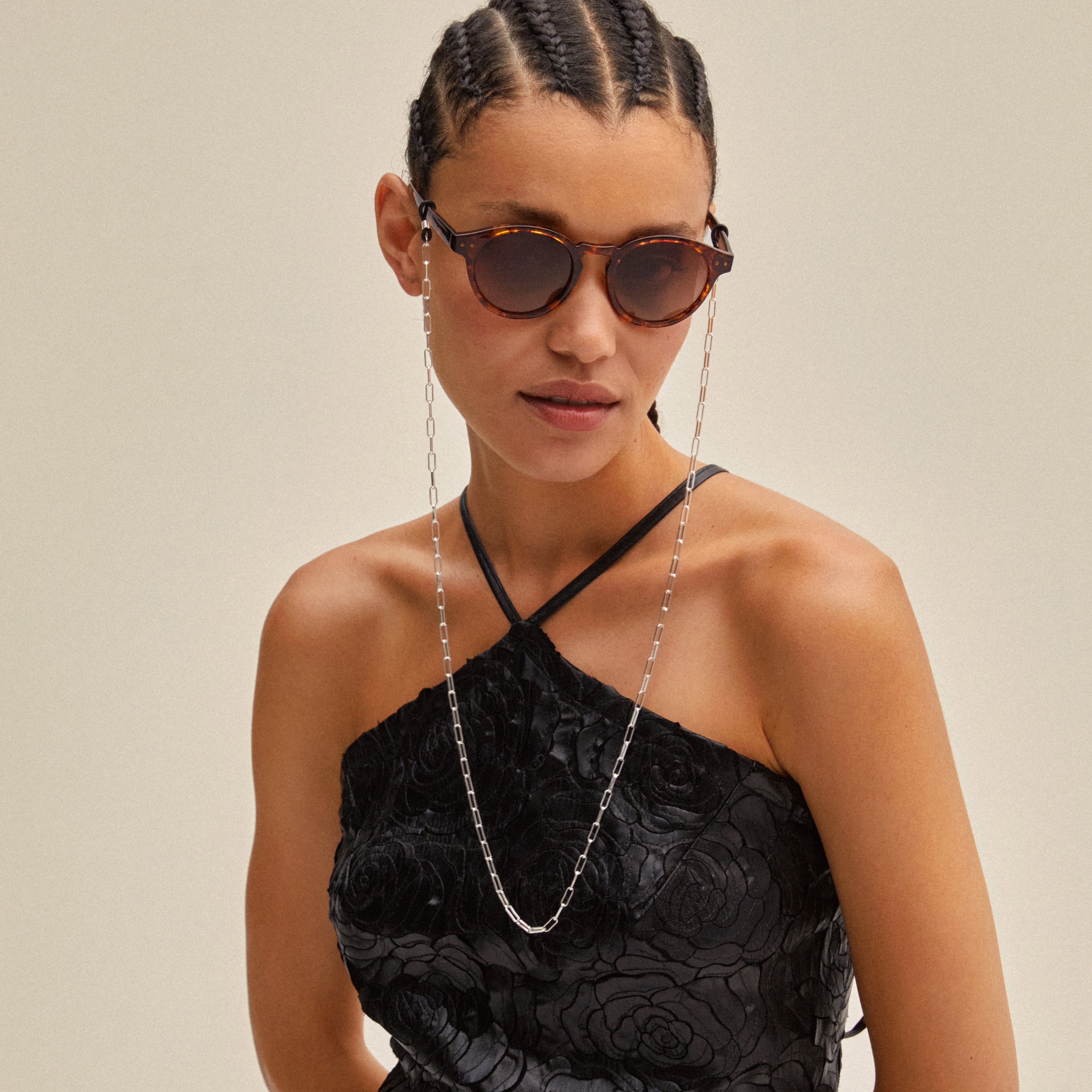 Woman wearing sunglasses with a PAOLA silver-plated chain from Pilgrim, showcasing a delicate, stylish accessory perfect for trendy, layered looks.