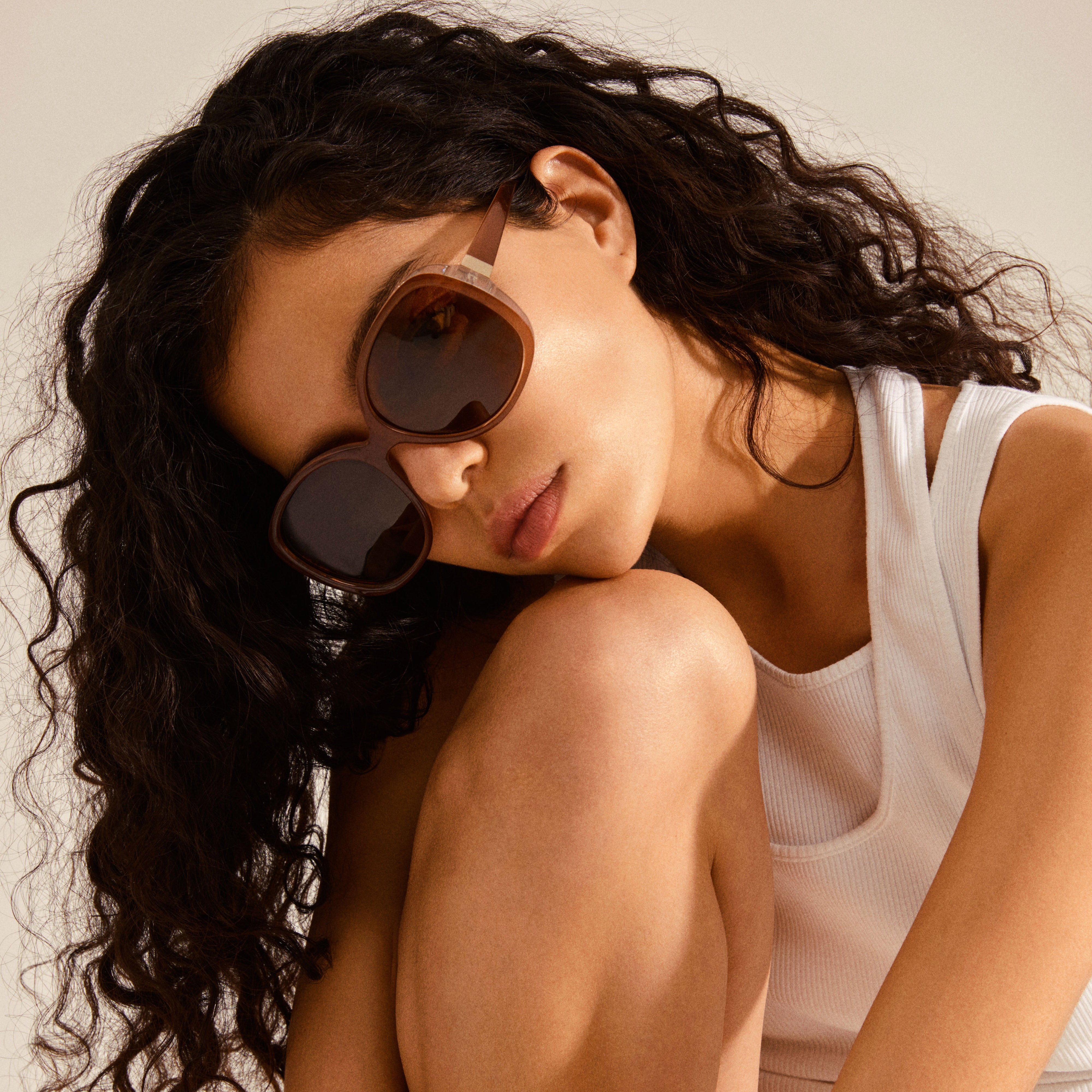 Woman wearing PARKER oversized retro sunglasses, sitting confidently. The sunglasses boast a 70's-inspired angular design, exuding vintage glamour and trendy summer vibes.