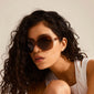 PARKER oversized retro sunglasses worn by a woman, showcasing a 70's-inspired design with a glamorous, angular shape, perfect for adding a stylish touch to summer outfits.