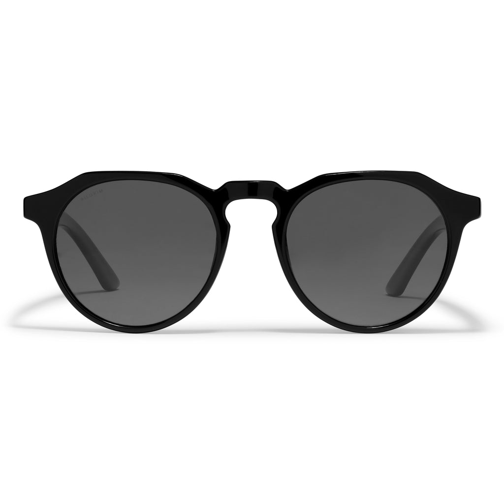 ALEJANDRA sunglasses by Pilgrim feature a modern angular frame with black lenses, offering a stylish twist on classic round designs, complete with UVA/UVB protection.