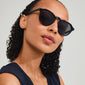Close-up of a woman wearing ALEJANDRA black sunglasses by Pilgrim, showcasing a modern round design with angular accents, offering a stylish spring accessory.