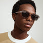 Man wearing ANNALISE sunglasses with angular, transparent smoky frame, perfect for summer outings; featuring UVA/UVB protection from Pilgrim's inclusive, trendy collection.