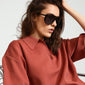 Woman wearing AMARI sunglasses black by Pilgrim, showcasing oversized dark lenses on trend.