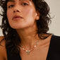 MSF necklace multi-coloured/gold-plated on a woman with curly hair, featuring a gold-plated coin pendant engraved with the MSF logo.