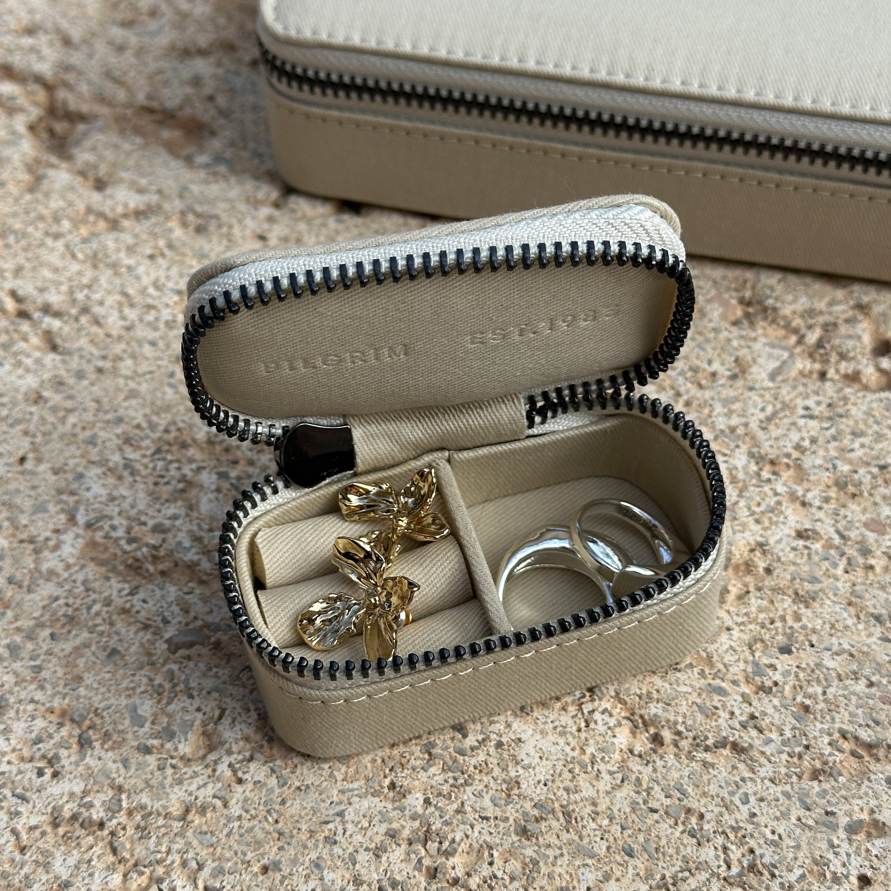 Mini jewelry box with zipper closure, showcasing a sleek, Scandinavian design by Pilgrim. Organizes rings, earrings, necklaces, and bracelets in a compact form.