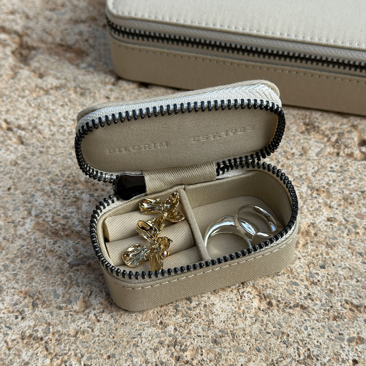 Mini jewelry box with zipper closure, showcasing a sleek, Scandinavian design by Pilgrim. Organizes rings, earrings, necklaces, and bracelets in a compact form.