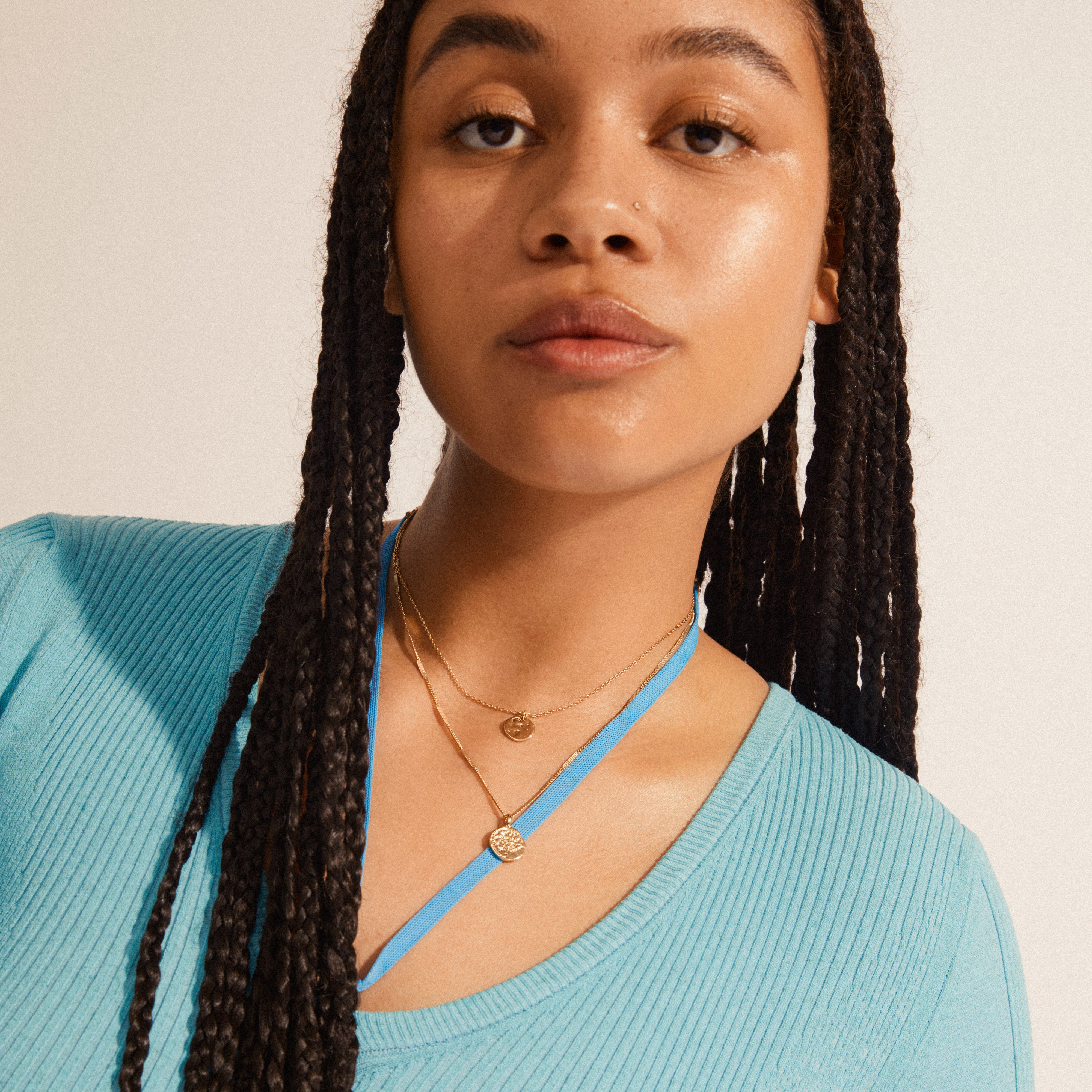 HAVEN 2-in-1 coin necklace gold-plated, elegantly layered on a young person, showcasing delicate pendants and dynamic chain links for a contemporary bohemian style.