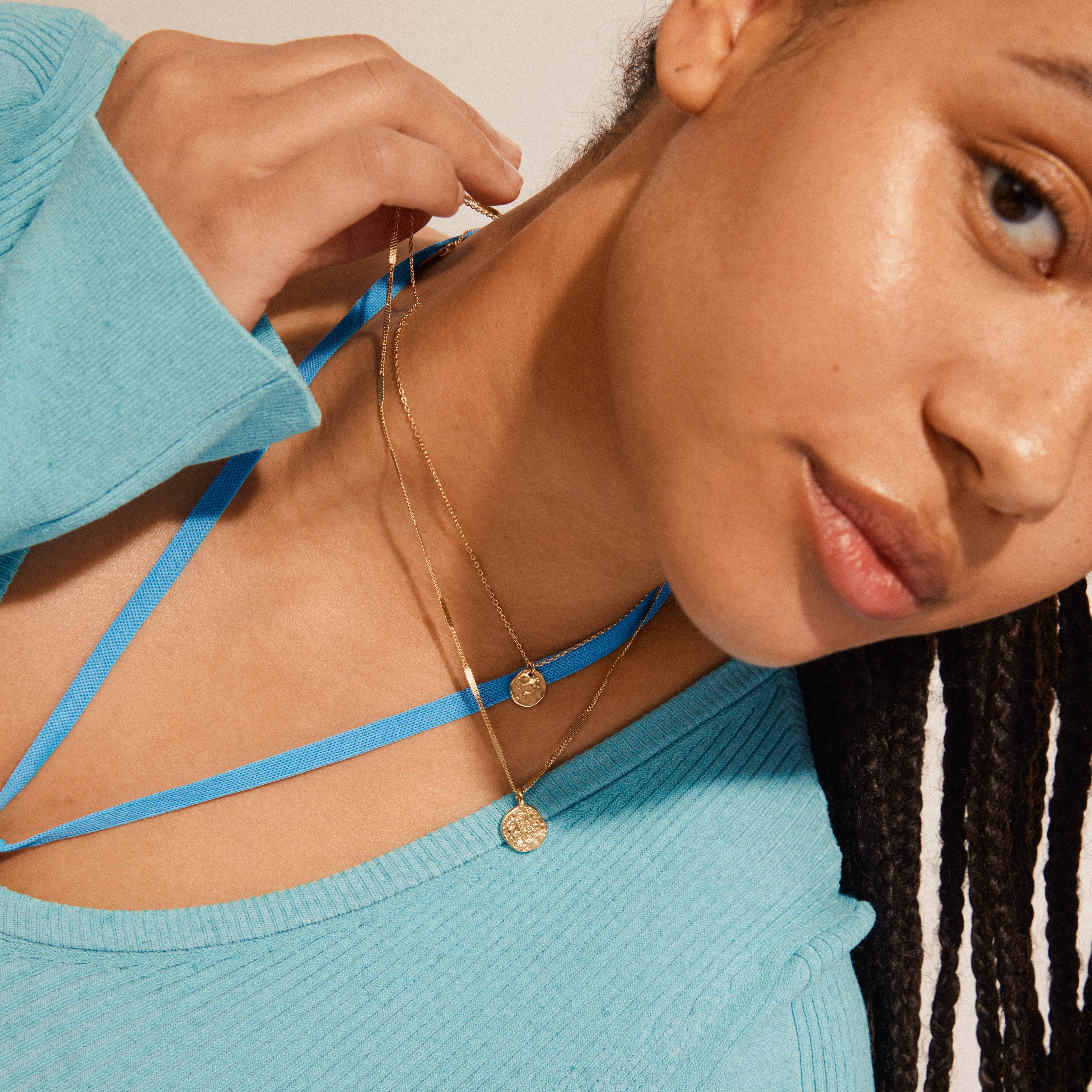 HAVEN 2-in-1 coin necklace gold-plated, features layered gold chains with coin pendants, elegantly worn over a light turquoise ribbed top, showcasing a modern bohemian style.
