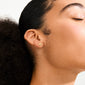 Close-up of an ear wearing a gold-plated peach-shaped stud from the HALO gift set earrings 3-in-1 set by Pilgrim.