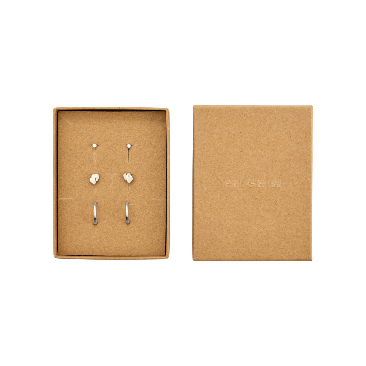 PILGRIM HALO gift set: Three pairs of silver-plated earrings, featuring crystal studs, heart studs, and huggie hoops in an open brown-kraft jewelry box.