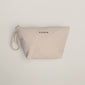 Light-beige canvas pouch with PILGRIM printed on front, featuring a zipper and fabric loop, designed to hold a gold-plated hoops set and foldable mirror.