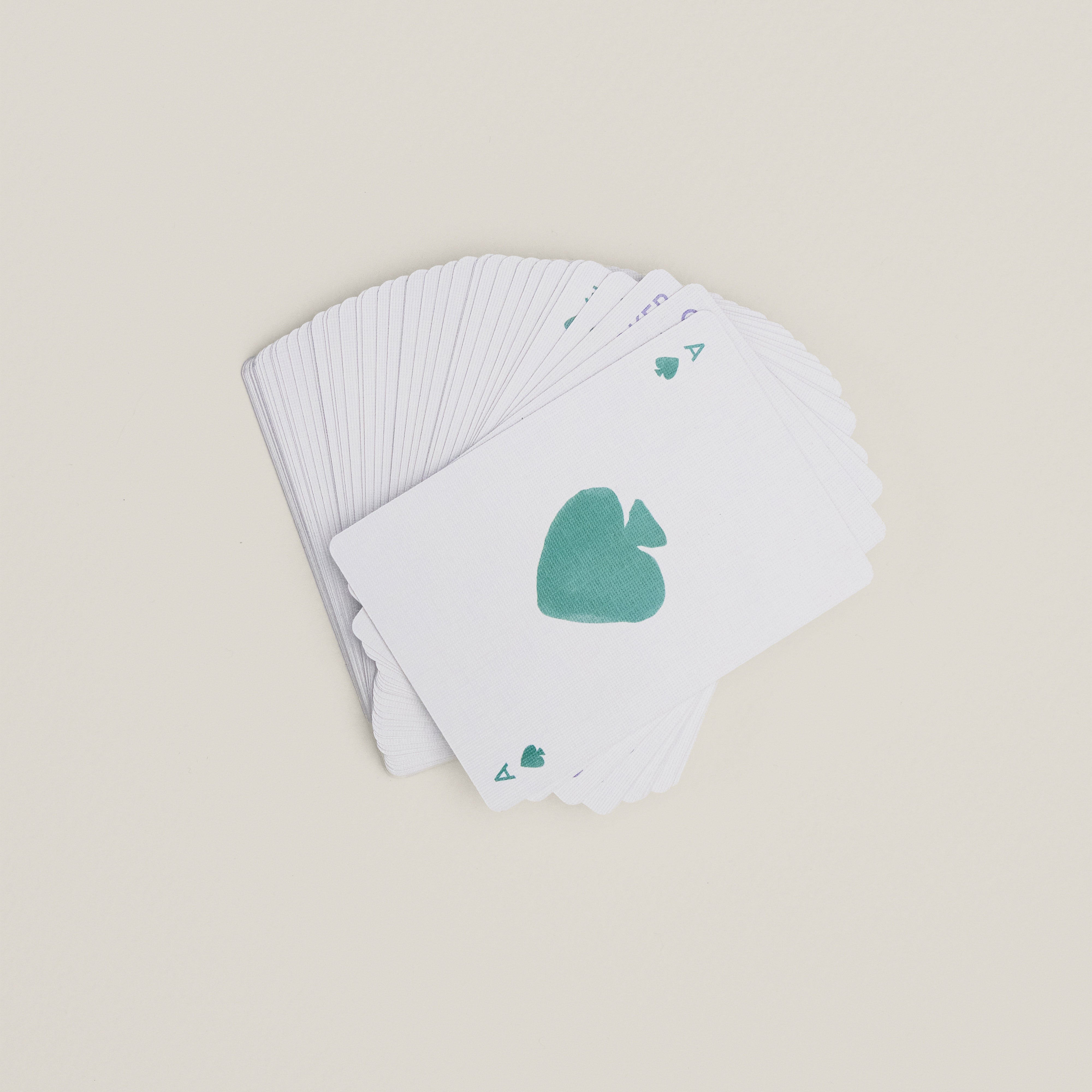 Fanned-out deck of playing cards with green-hued Ace of Spades on top, symbolizing Pilgrim's Limited Goodie Bag of trendy gold-plated hoops and foldable mirror.