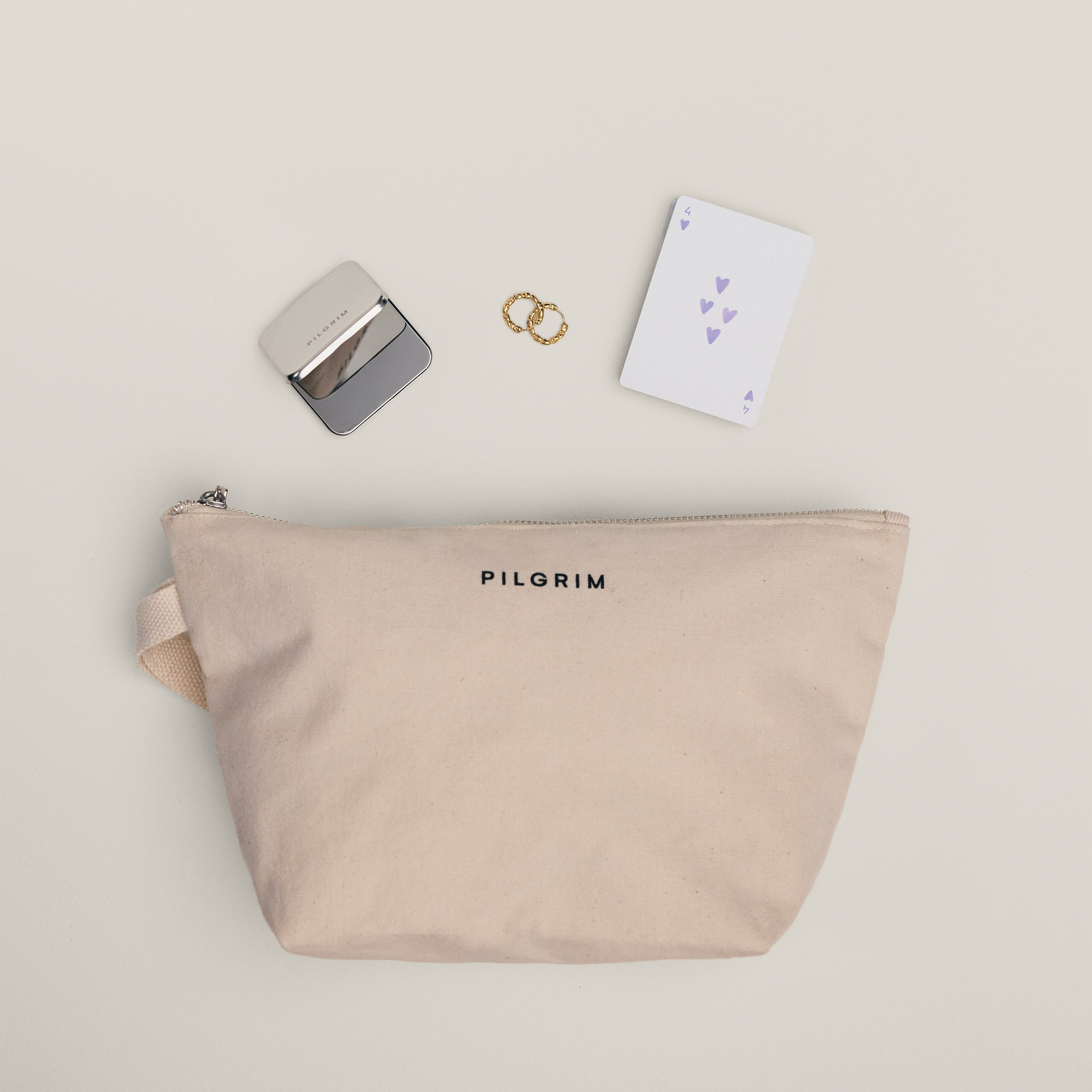 Limited Goodie Bag features twisted-gold hoop earrings, a fold-over mirror, and a PILGRIM canvas pouch—everyday essentials crafted from 99% recycled materials.