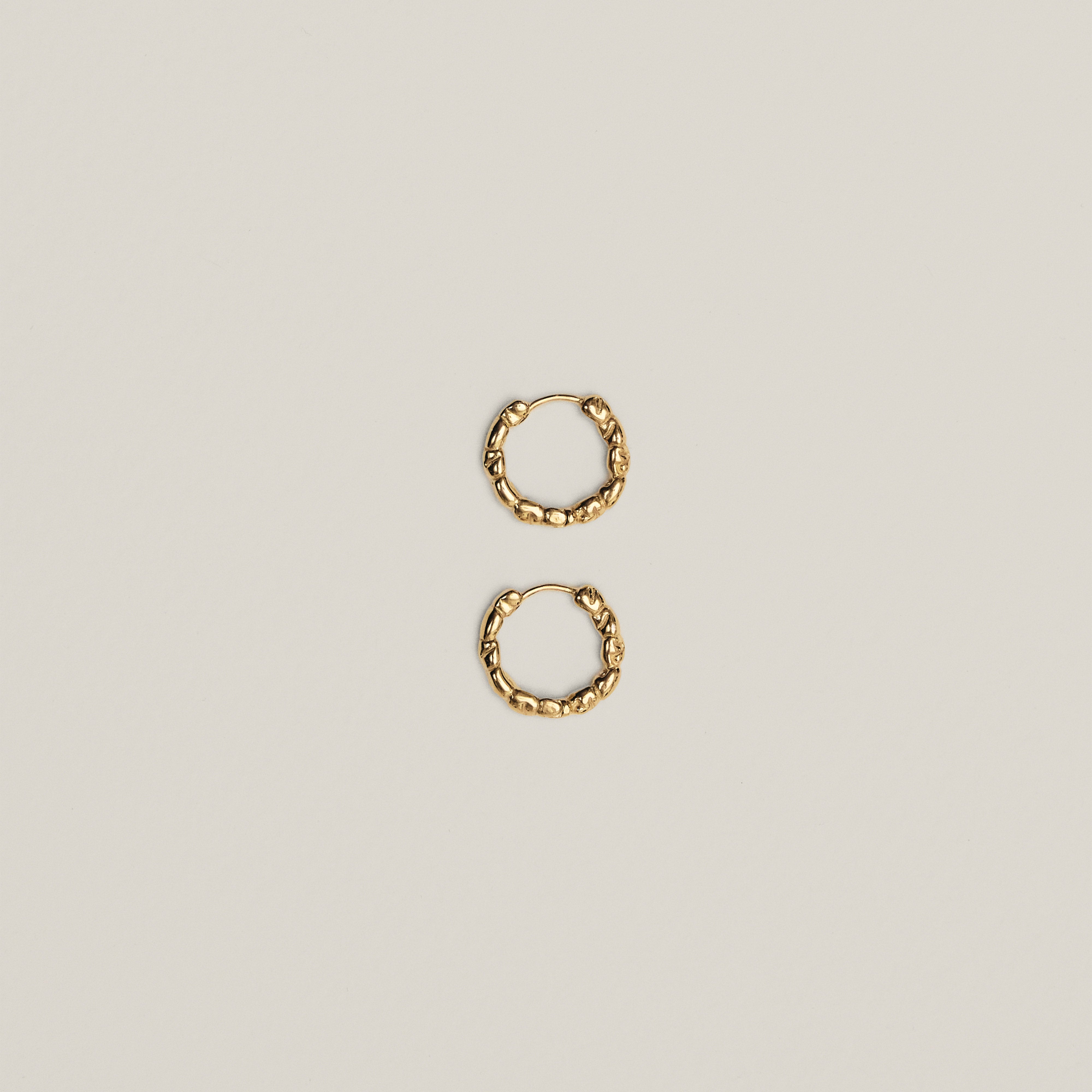 Textured gold hoop earrings with organic pebble-like design, part of the Limited Goodie Bag by Pilgrim, showcasing trendy, minimalist style crafted from recycled materials.