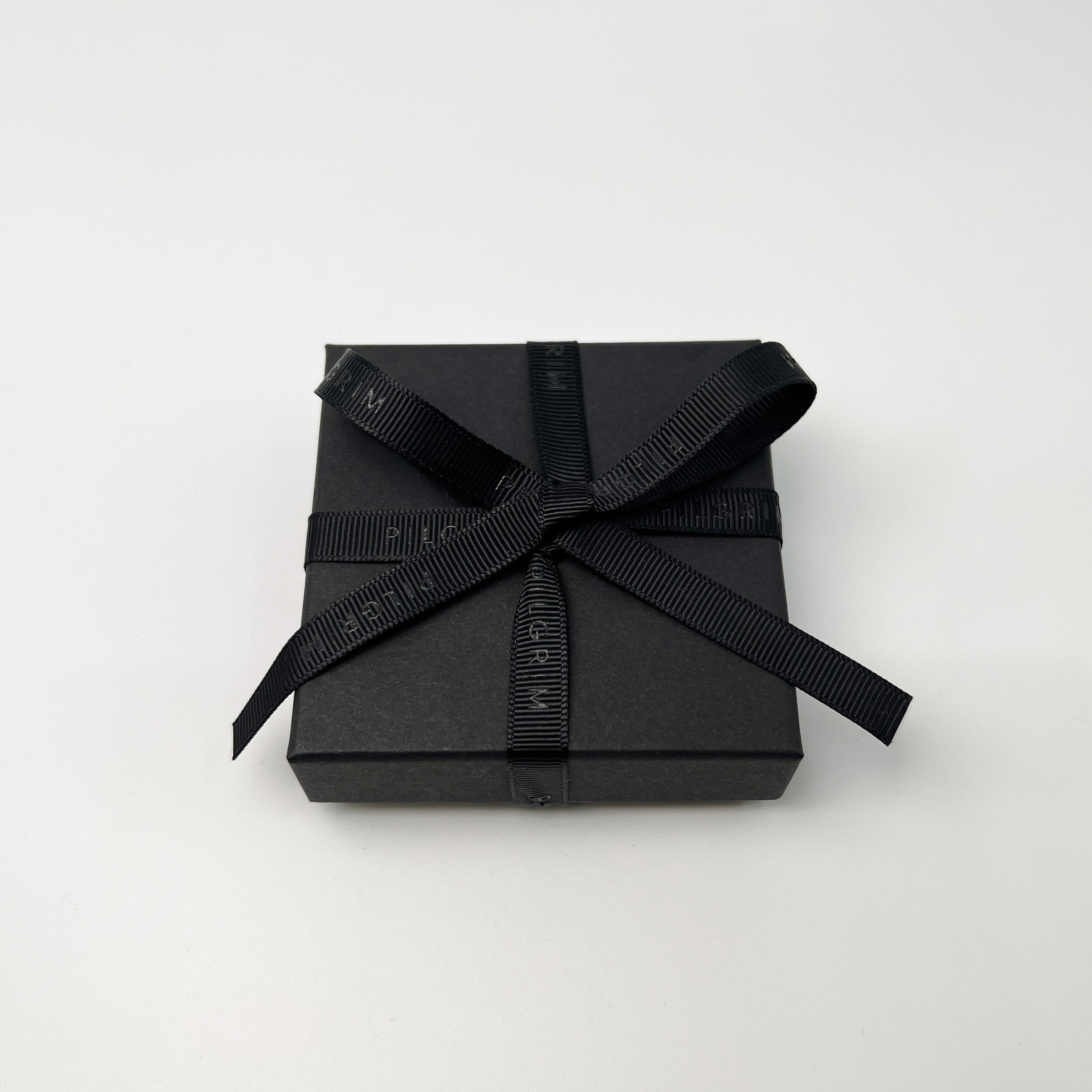 Luxurious gift box with black ribbon, perfect for Pilgrim's eco-friendly jewelry packaging, enhancing elegance with sustainable materials. Ideal for rings, earrings, and small necklaces.